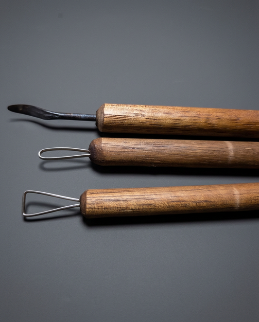 Three clay detailing tools with wooden handles, grey studio background