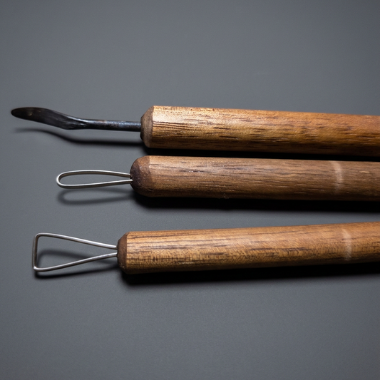 Three clay detailing tools with wooden handles, grey studio background