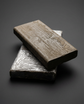 Two blocks of wax based sculpting clay, one in its foil wrap, grey studio background