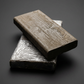 Two blocks of wax based sculpting clay, one in its foil wrap, grey studio background
